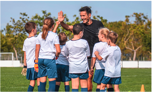 Sean coaching young players, high-five with kids in white kit